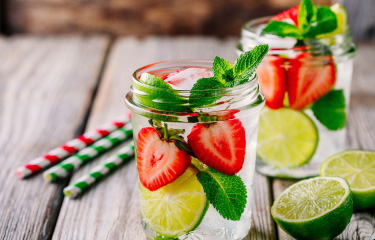 a glass of water strawberries, limes, and mint