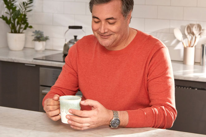 Man sitting with a cup at an island in a kitchen